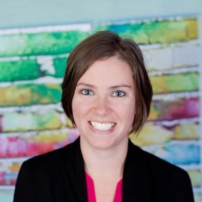 Chiropractic Assistant Brittany Smiling In Front Of Colorful Bricks
